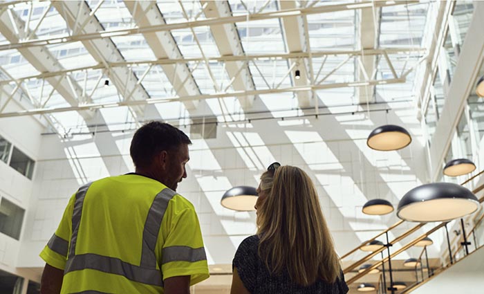 一名建筑工人和他的同事从一幢翻新的建筑里抬头看天窗装置