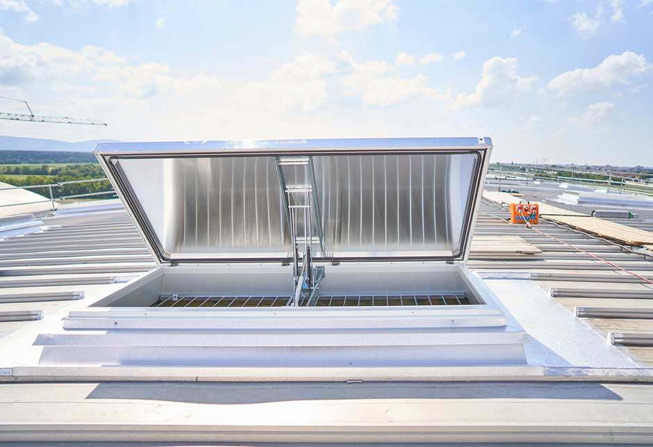 Świetliki dachowe z aluminiowymi (ciemnymi) klapami i ochroną przed upadkiem w pozycji wentylacyjnej
