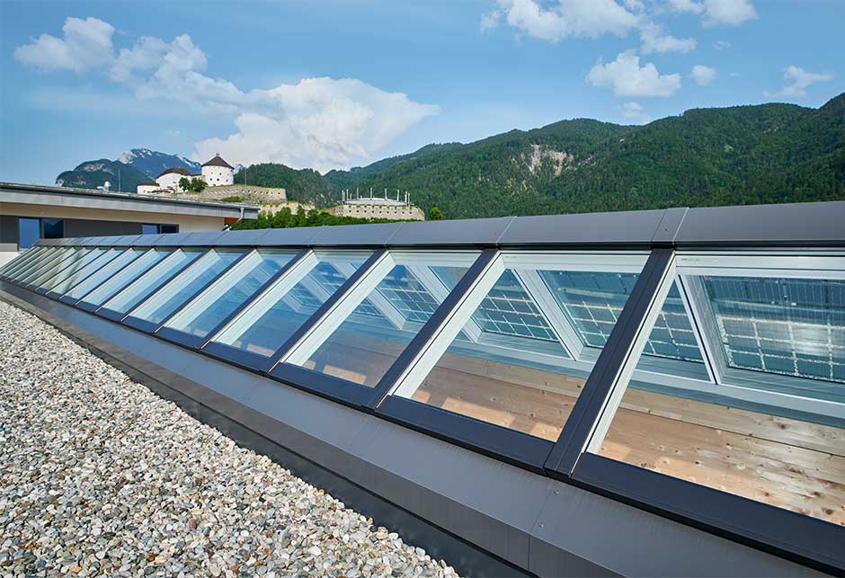 Widok z dachu na pasmo świetlne dwuspadowe 25–40° z panelami fotowoltaicznymi, magazyn w Kufstein, Austria